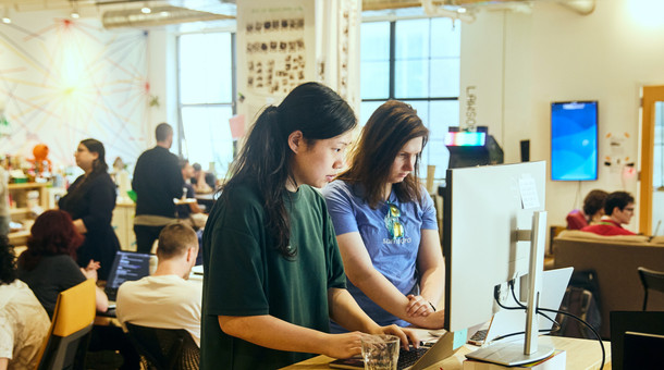 Recursers pairing at a standing desk on the loud, collaborative floor